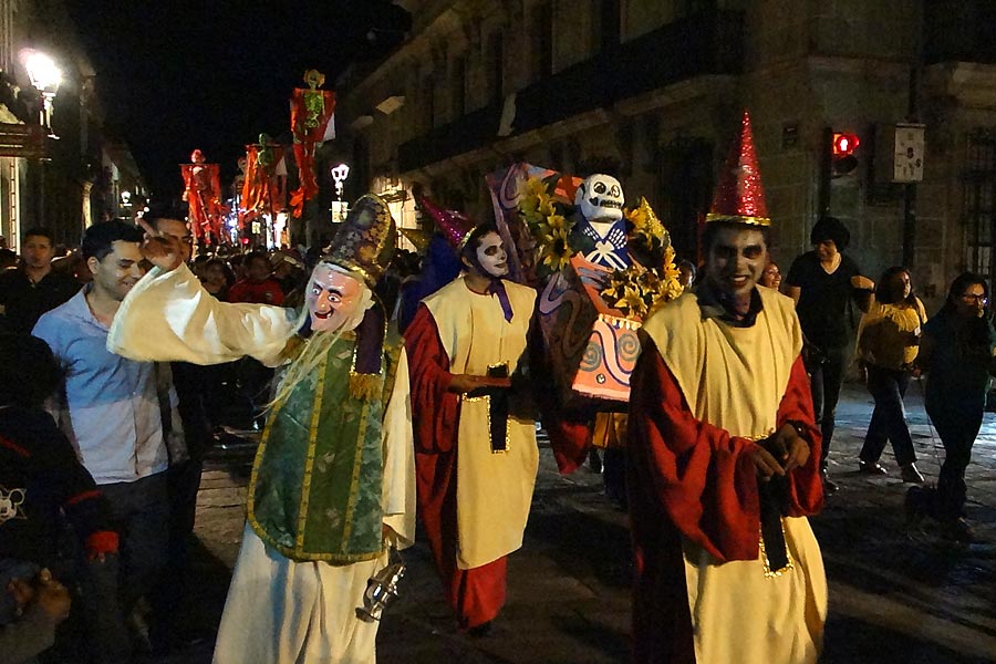 Band dan orang-orang dengan kostum berbaris di jalan-jalan di oaxaca pada hari kematian