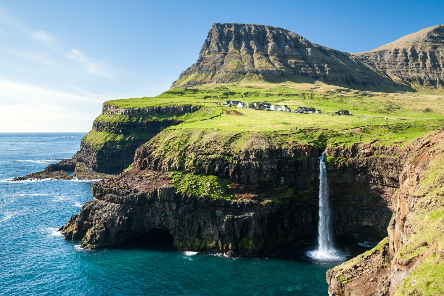 Waterfall on faroe islands and the village Gasadalur in background