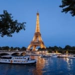Eiffel Tower, cruise boats and bridge on Seine river at night in Paris, France