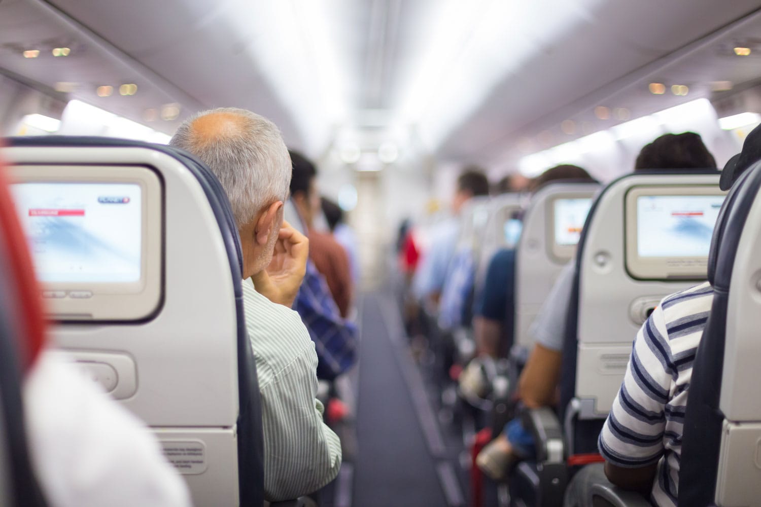 Interior pesawat dengan penumpang di kursi menunggu lepas landas.
