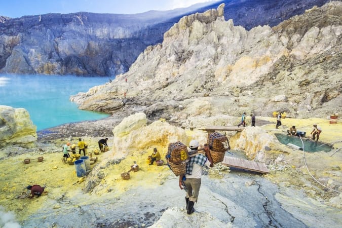 Sulfur miner hiking down into the crater of Kawah Ijen volcano in East Java, Indonesia.