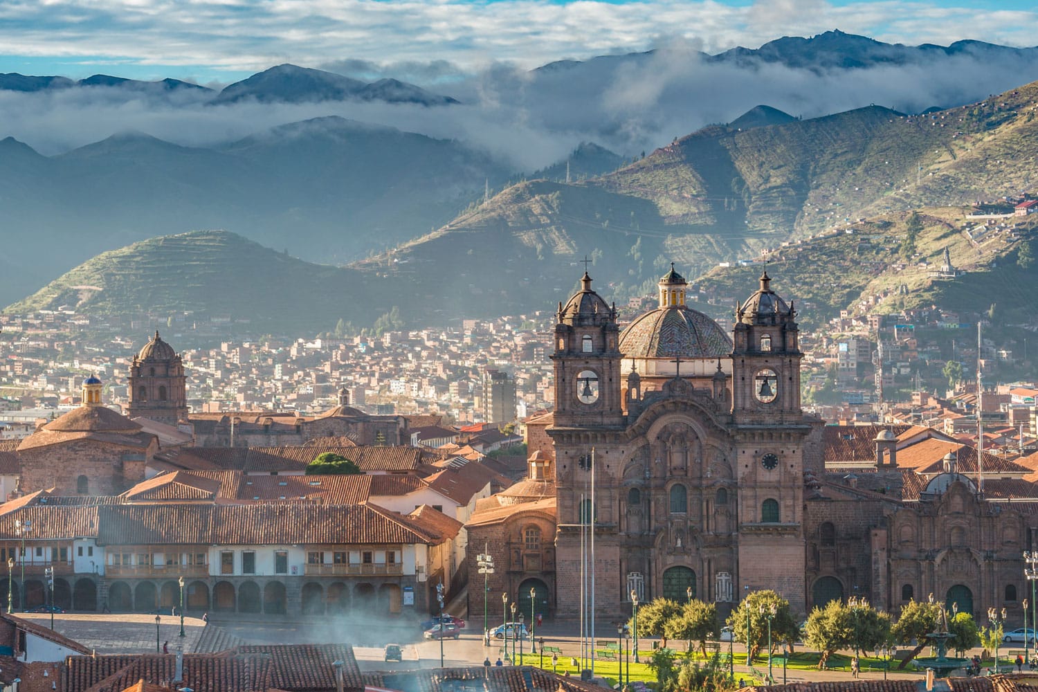 Matahari pagi terbit di Plaza de armas dengan Gunung Adean dan gugusan awan, Cusco, Peru