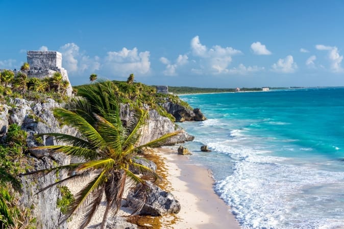 Ruins of Tulum, Mexico and a palm tree overlooking the Caribbean Sea in the Riviera Maya, Mexico