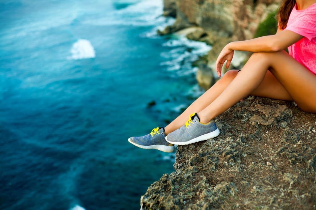 Women sitting on a cliff showcasing her shoes