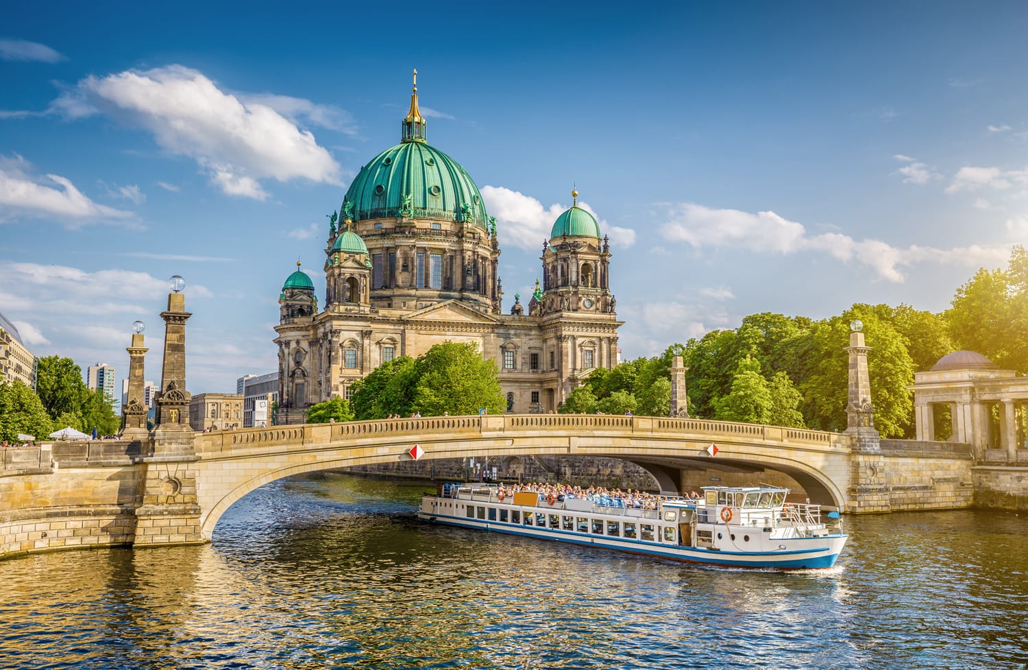Pemandangan indah Katedral Berlin (Berliner Dom) yang bersejarah di Museum Island yang terkenal dengan kapal yang melewati jembatan Friedrichsbrucke di sungai Spree dalam cahaya malam keemasan saat matahari terbenam di musim panas, Berlin, Jerman