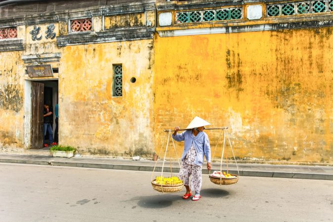Vietnamese woman street seller In hoi an Vietnam in ancient town Hoi An with view of typical yellow houses