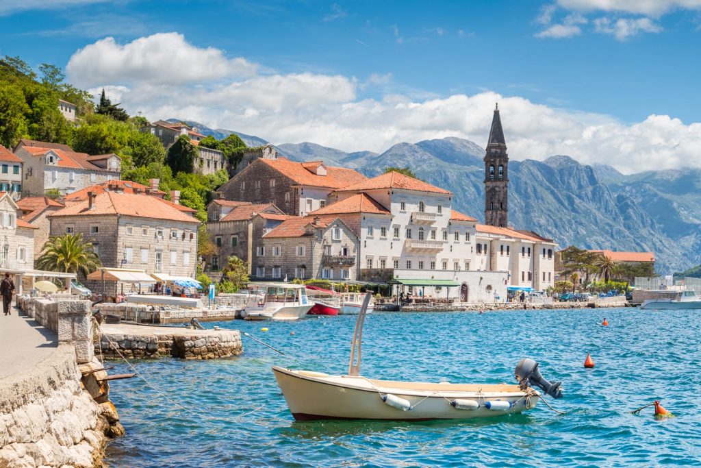 Scenic panorama view of the historic town of Perast located at world-famous Bay of Kotor on a beautiful sunny day with blue sky and clouds in summer, Montenegro