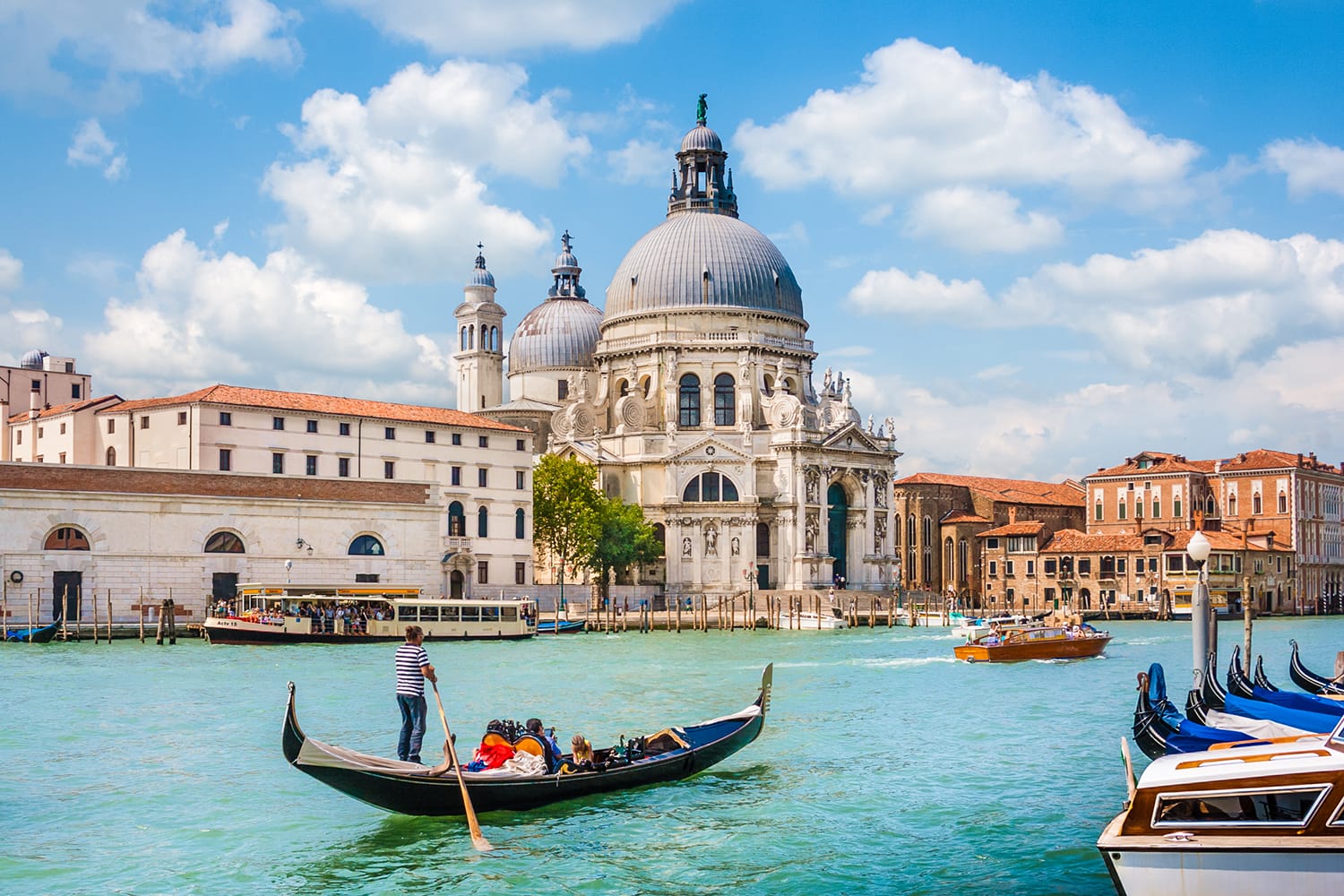 Beautiful view of traditional Gondola on Canal Grande with Basilica di Santa Maria della Salute in the background on a sunny day in Venice, Italy