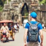 ourist in the ancient city. Young man with backpack coming to ancient monuments. Siem Reap, Cambodia