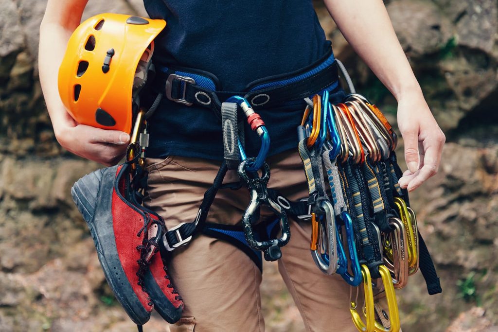 Woman standing with climbing equipment and helmet outdoor, front view.