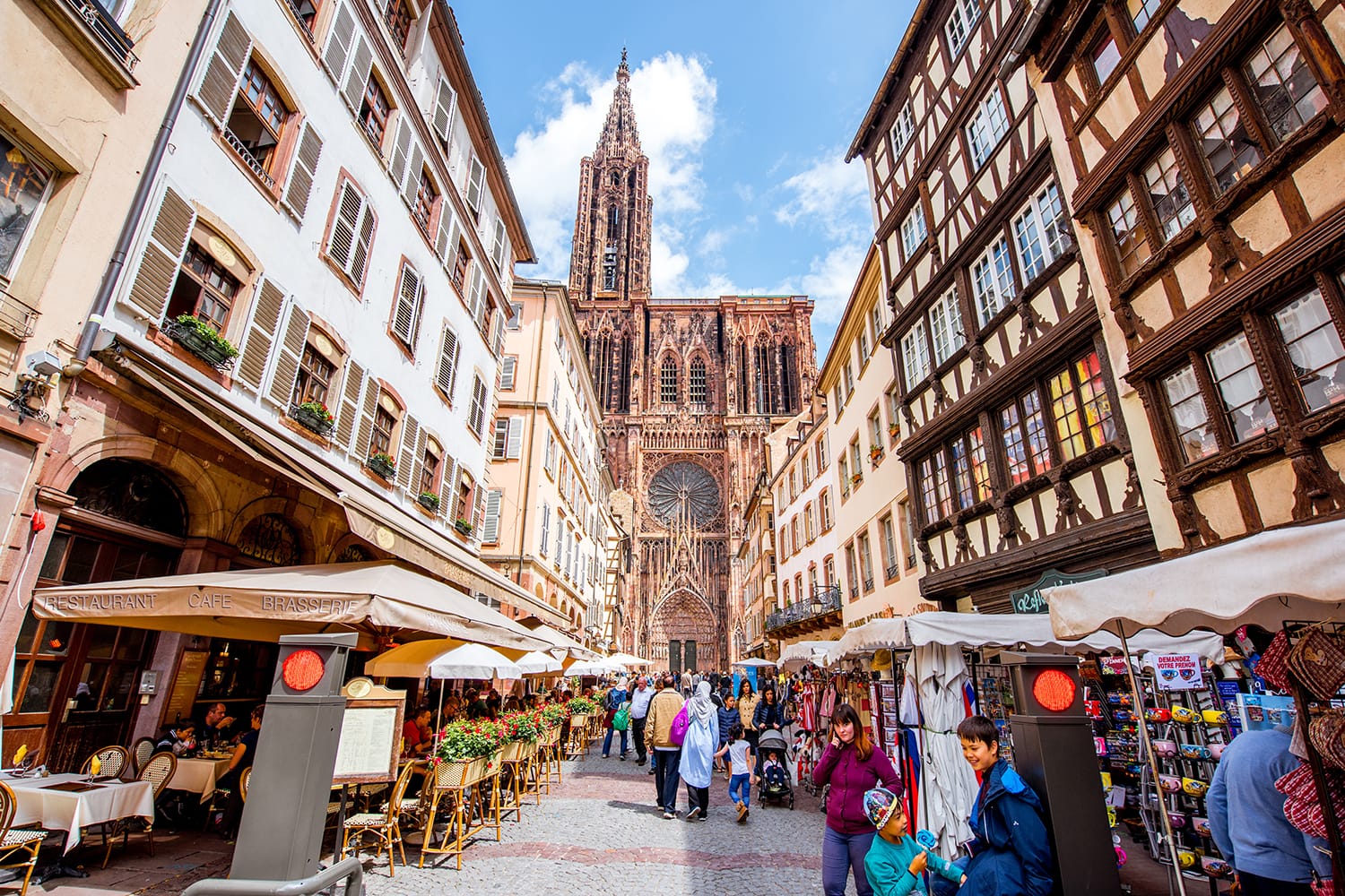 View on the crowded street with beautiful old buildings and Notre-Dame cathedral in Strasbourg city, France