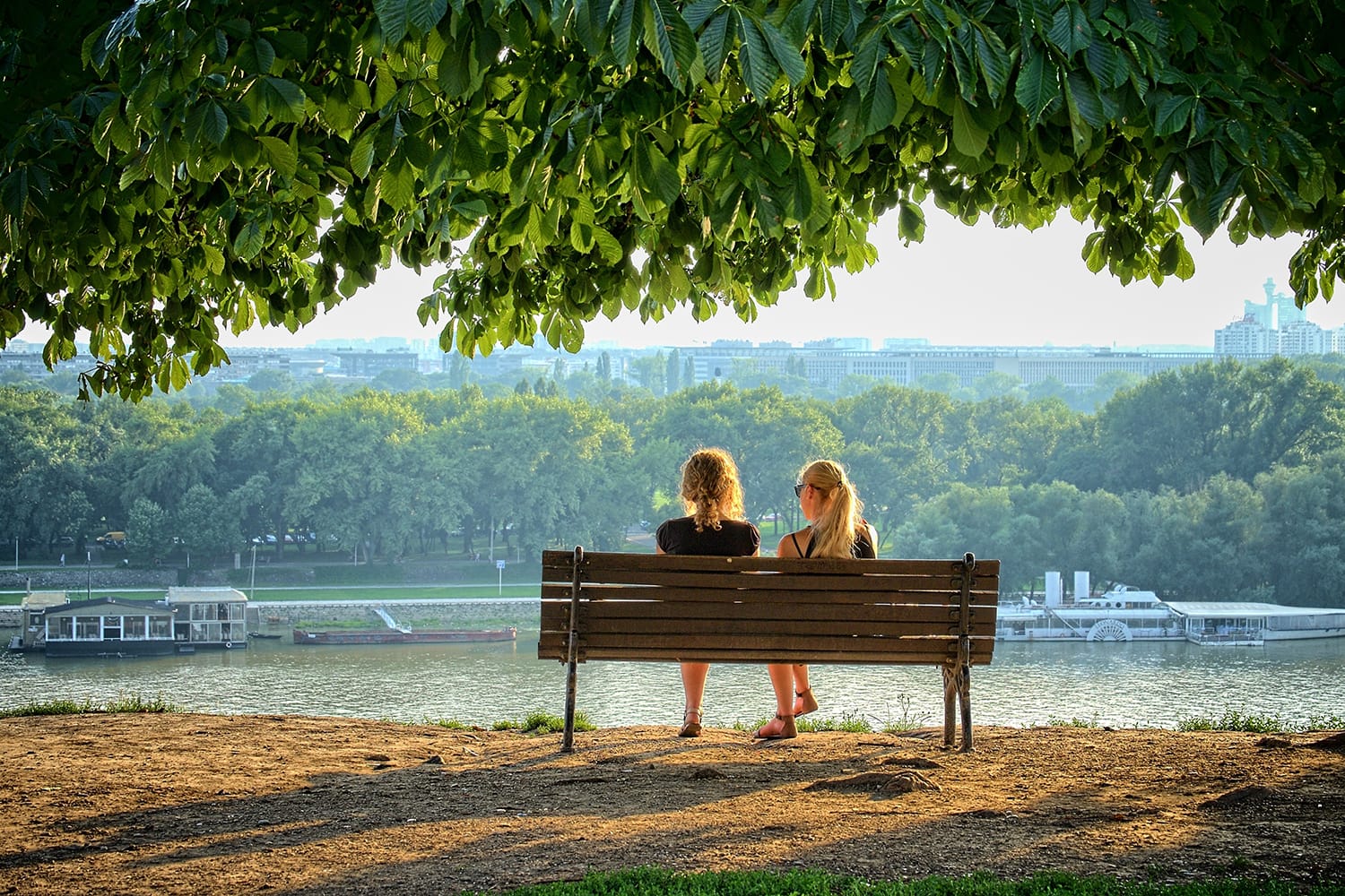 Two young women sitting on a bench of Kalemegdan Fortress in front the Danube rivers in Belgrade, Serbia