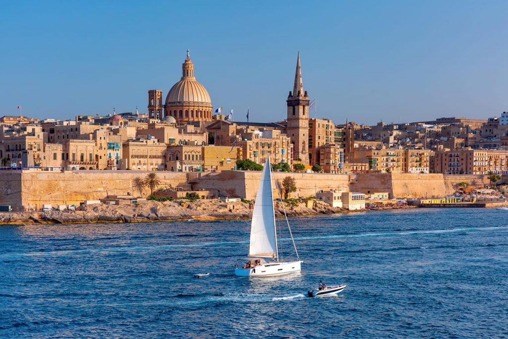 White yacht and Old town of Valletta with churches of Our Lady of Mount Carmel and St. Paul's Anglican Pro-Cathedral, Valletta, Capital city of Malta