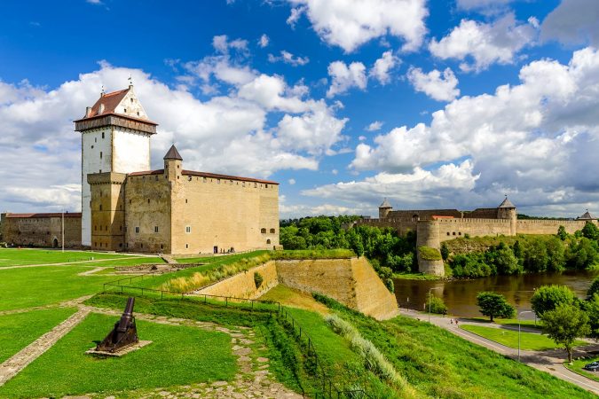 Beautiful summer view of Narva Castle with tall Herman's tower and the ancient Russian fortress in Ivangorod, the monument and popular tourist attraction