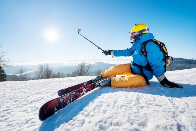 Skier sitting on the ski slope taking a selfie