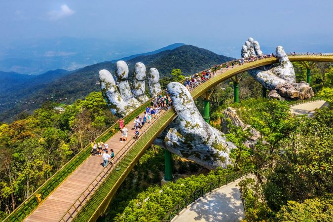 Aerial view of the Golden Bridge is lifted by two giant hands in the tourist resort on Ba Na Hill in Da Nang, Vietnam