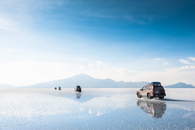 Off-road cars driving through Salar de Uyuni salt flat in Bolivia