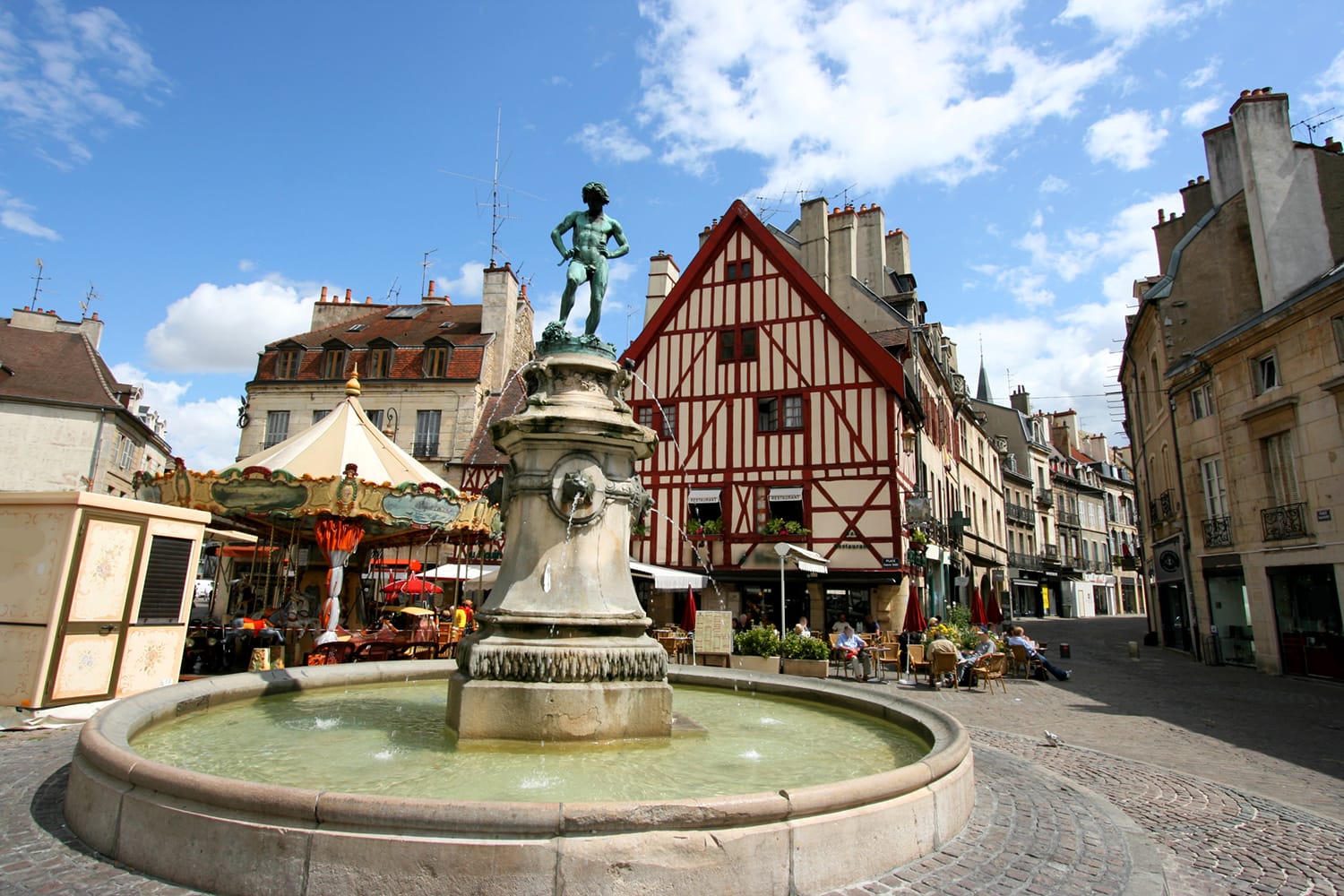 Famous fountain, characteristic houses and colorful carousel in Dijon, Burgundy, France. Place Francois Rude.