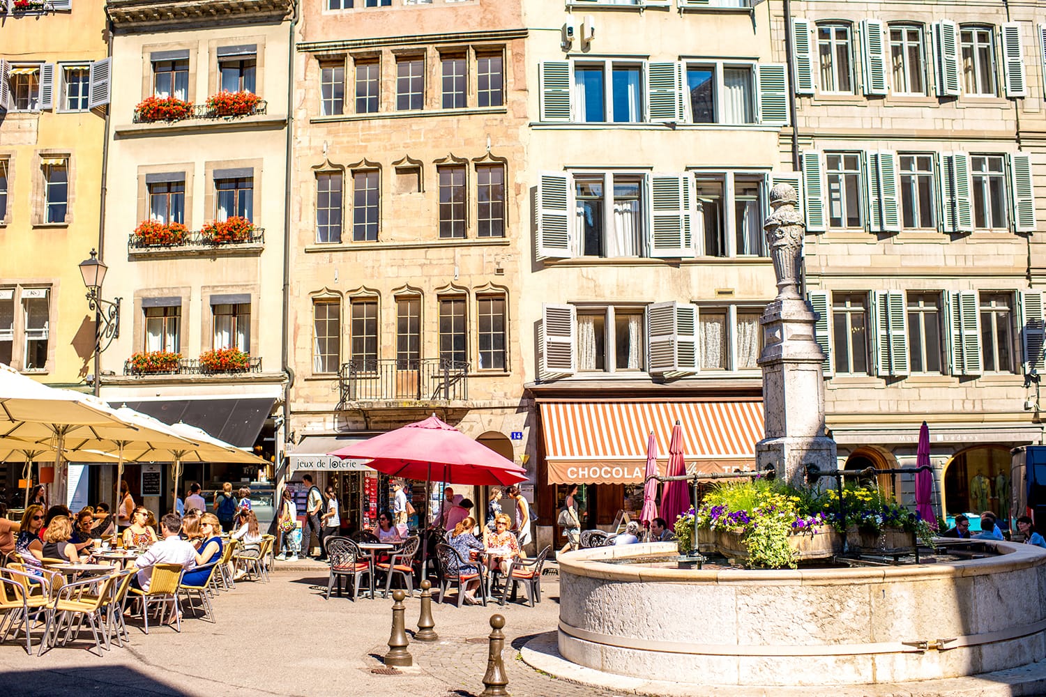 Bourg-de-four square with people sit in cafes and restaurants. It is the oldest square and the most popular meeting place in Geneva, Switzerland