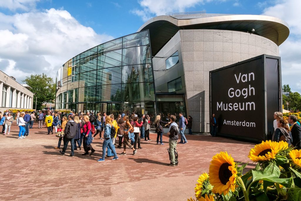 crowd in front of the new wing of the Van Gogh Museum with sunflowers in the foreground