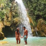 Lovely couple alone in deep forest waterfall from mountain gorge at hidden tropical jungle in Cebu Island in Philippines