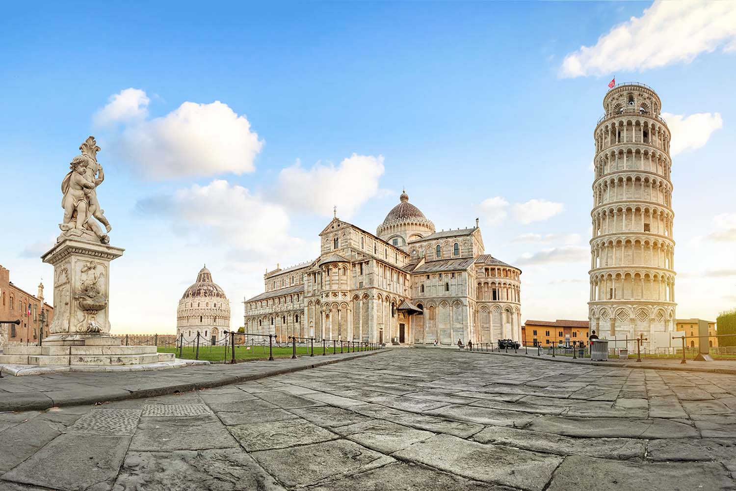 Panoramic low angle view of Piazza del Duomo square with Leaning Tower, Pisa Cathedral and Putti Fountain