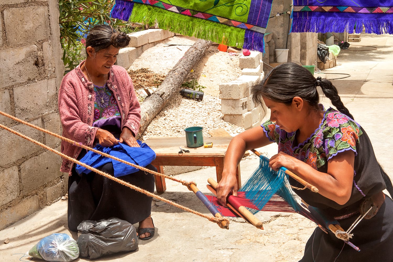 Indigenous Tzotzil women weaving a traditional Huipil at the loom in Zinacantan, Mexico