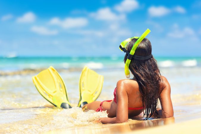 Woman laying on beach with snorkel gear