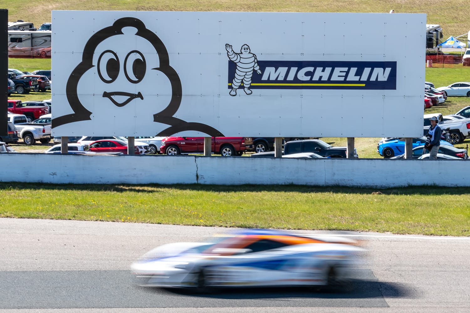 Michelin Tire billboard at Canadian Tire Motorsport Park as McLaren 720S speeds by on-track during a race. Bowmanville, Canada
