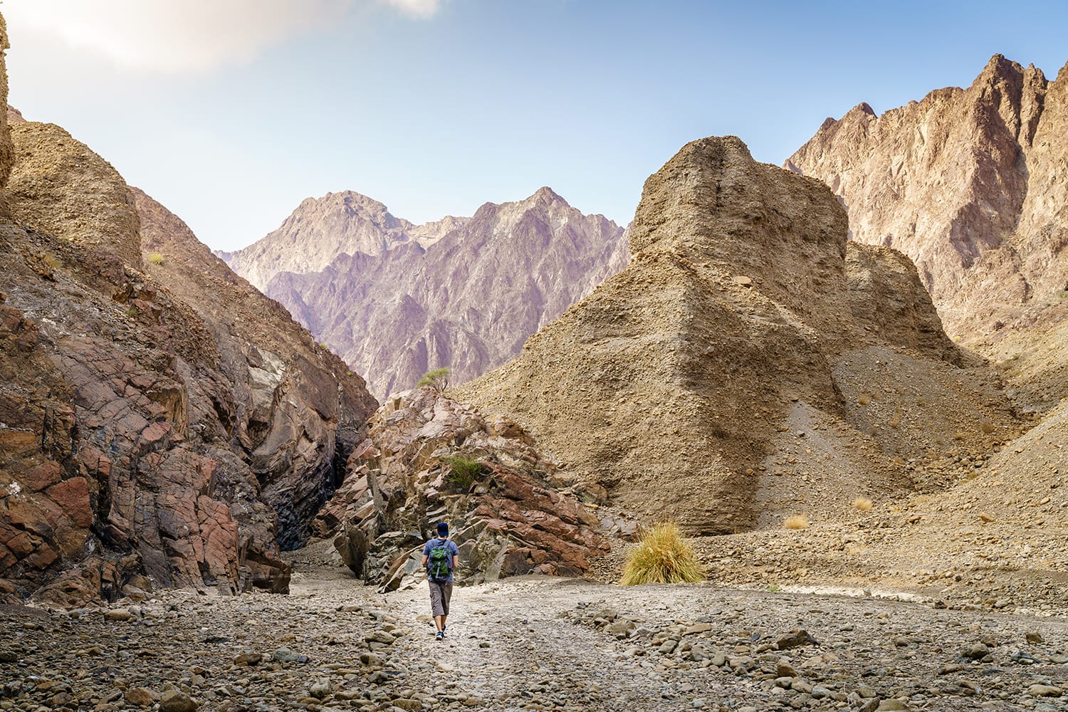 A man is hiking through a wadi in Hajar Mountains near Hatta, UAE