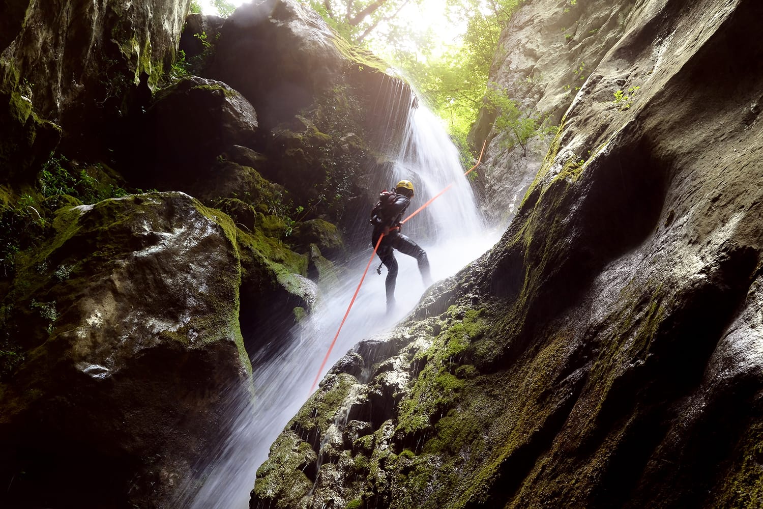 A man rappelling down a waterfall