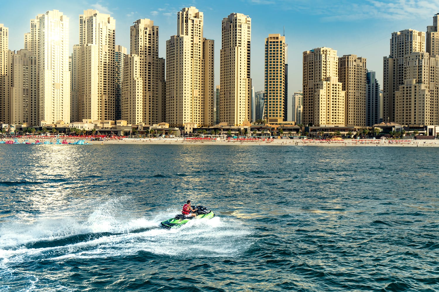A man doing a water sport in the water with the Dubai skyline in the background.