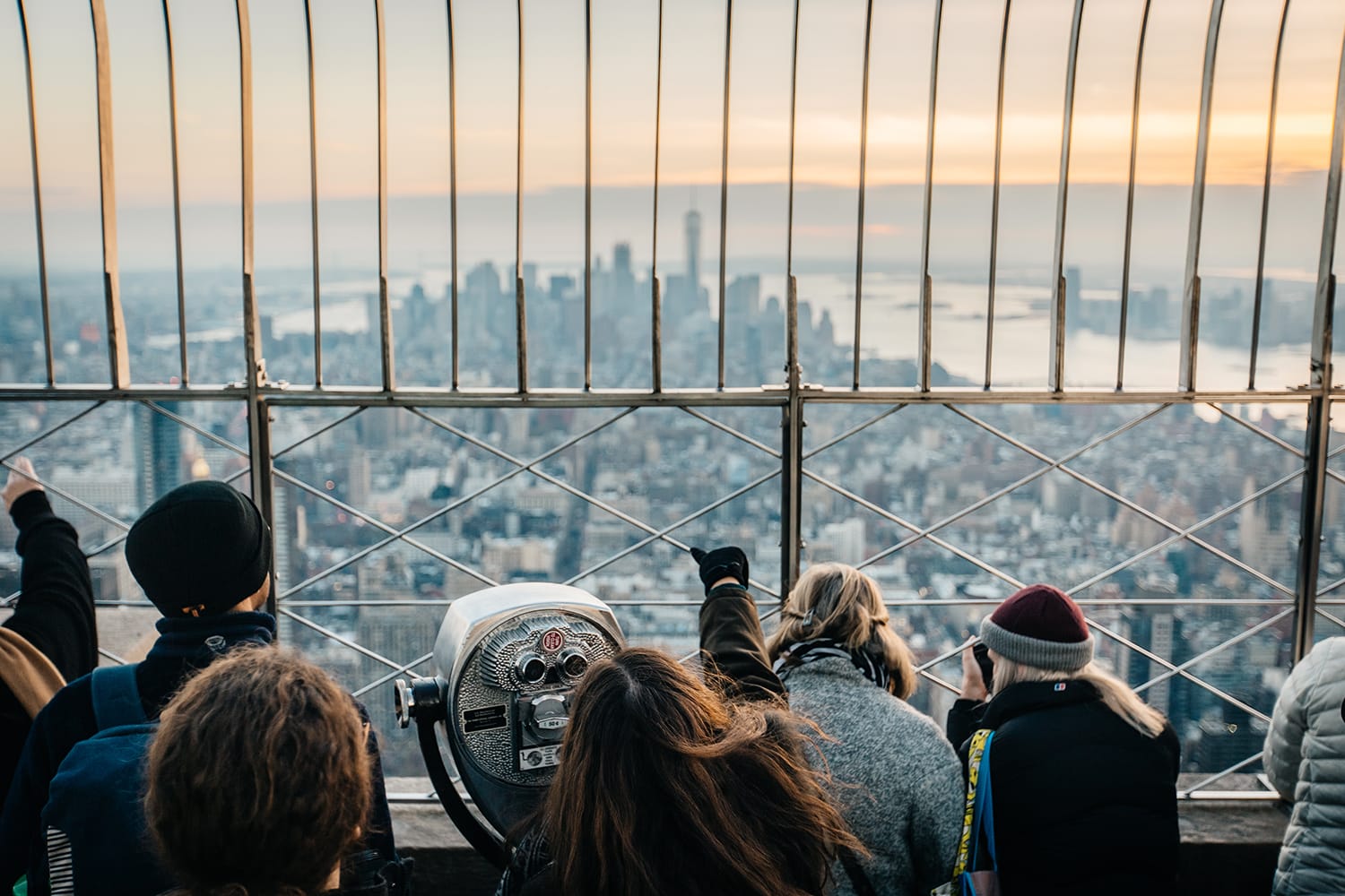 Tourists stand on the viewing platform at the Empire State Building looking at the city skyline