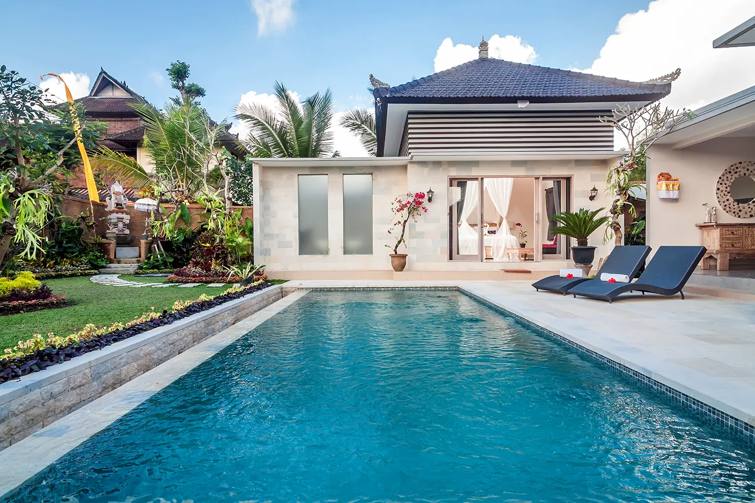 Exterior luxury villa in Bali with a garden and swimming pool outdoors.
