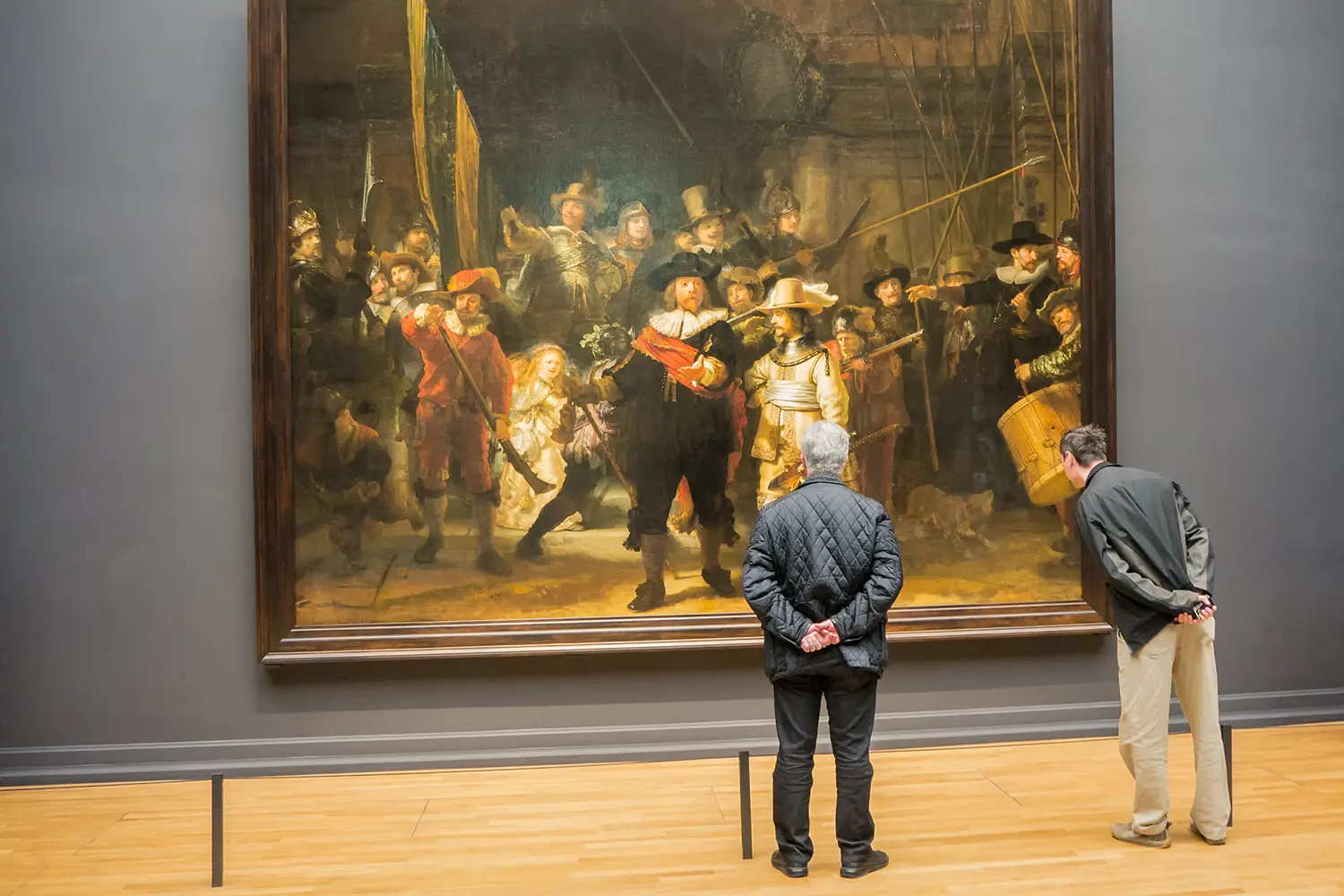 Tourists in one of the rooms of national Rijksmuseum scrutinize the world famous Nightwatch painting by Rembrandt