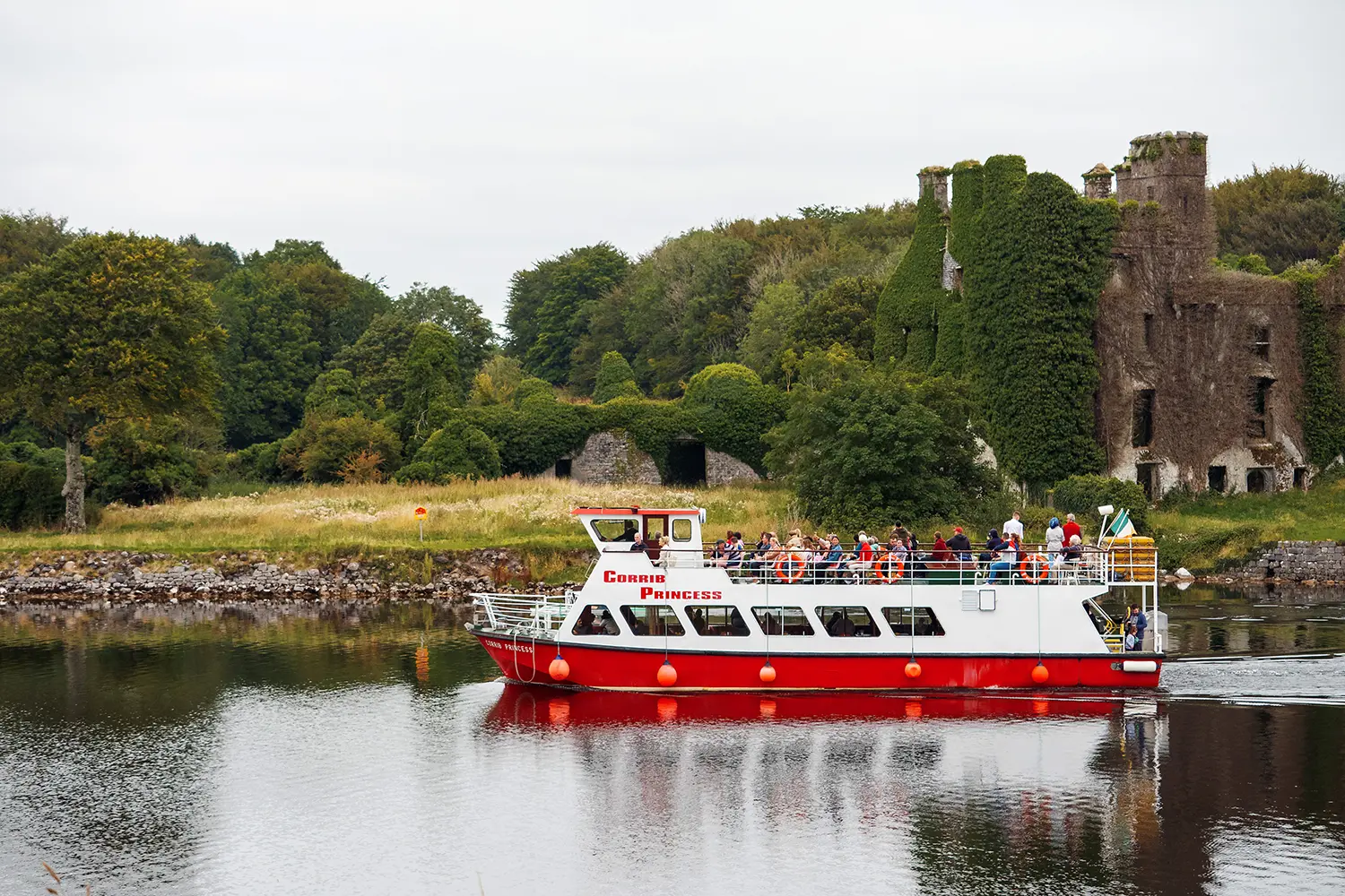  Corrib princess small cruise ship with tourist on board passing by popular town landmark Menlo castle
