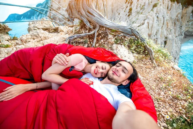 Young couple lying in red sleeping bag