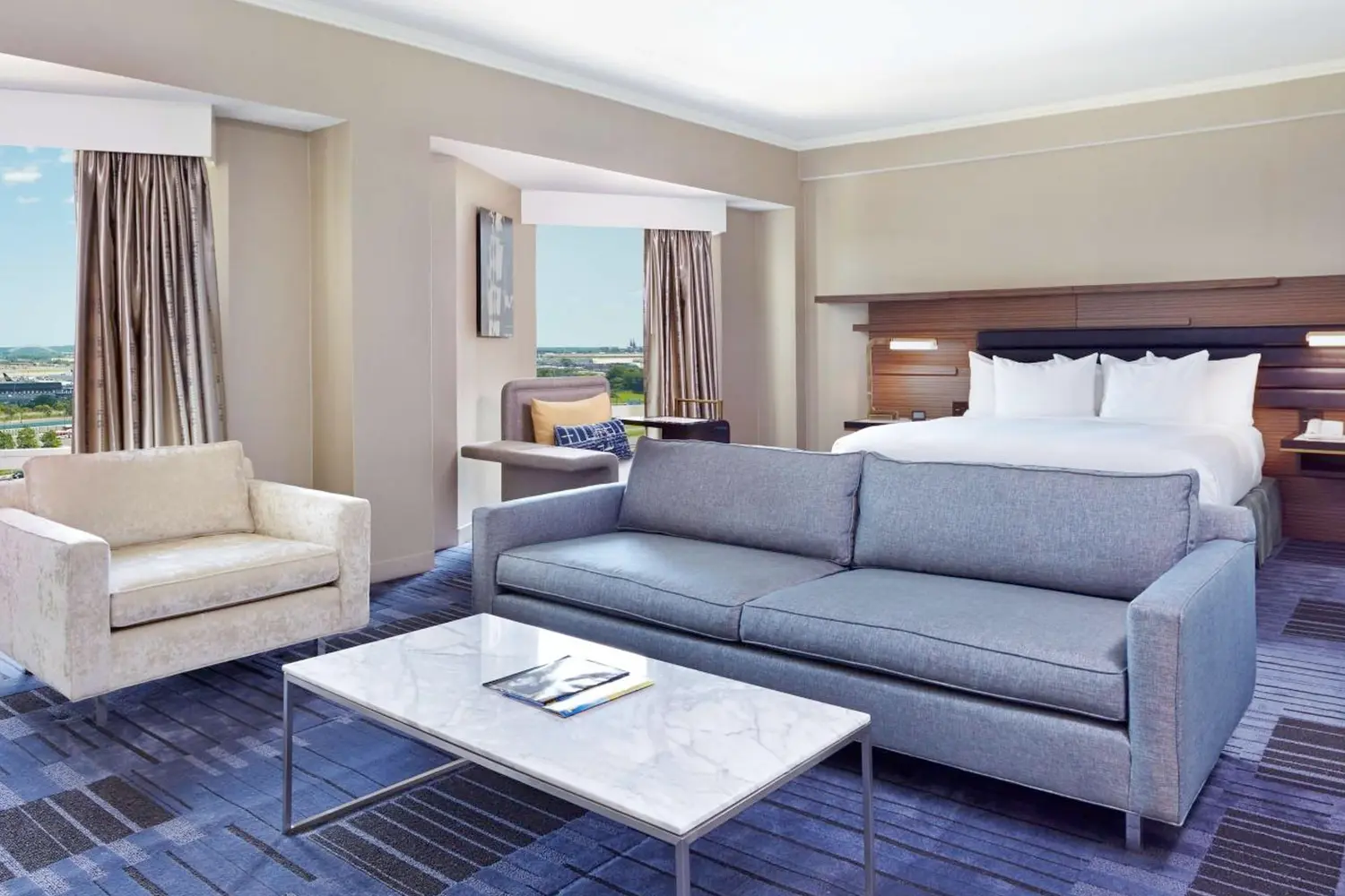 A room with a bed, couch, and table at Hilton Newark Airport