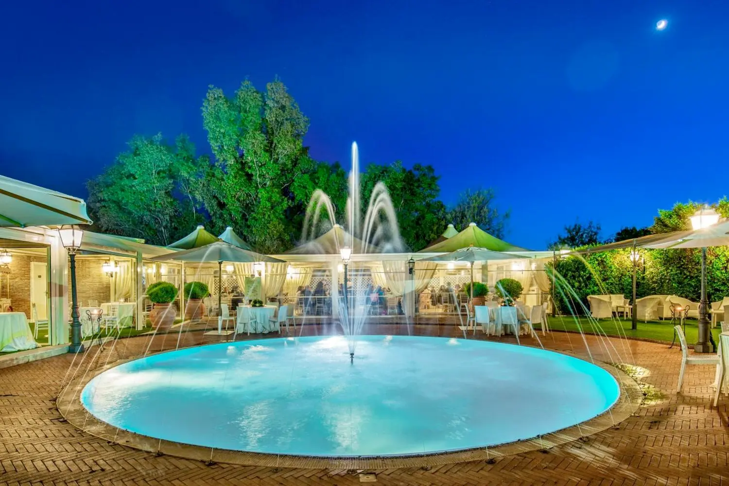 An outdoor area with a fountain, chairs and umbrellas at Hotel Piccolo Borgo