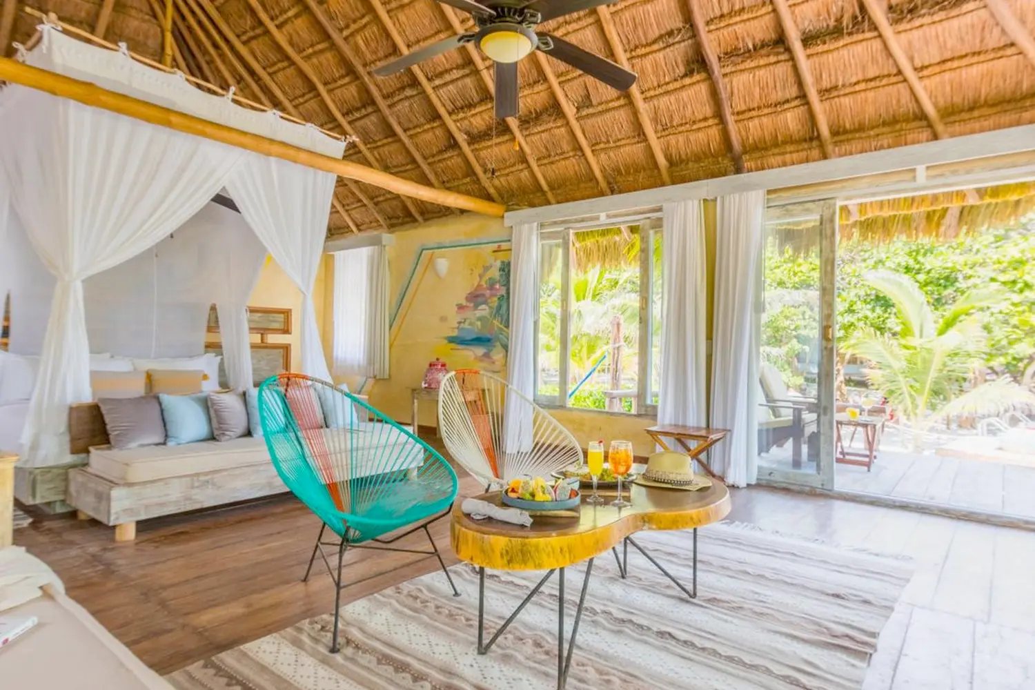 A room with a couch, bed, table, and patio with a pool at Villa Pescadores Tulum