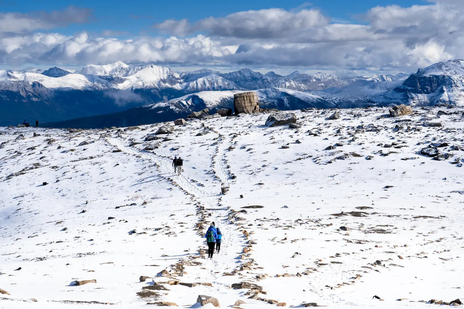 Tourists hike along a snow covered mountain top trail in Jasper National Park, Canada