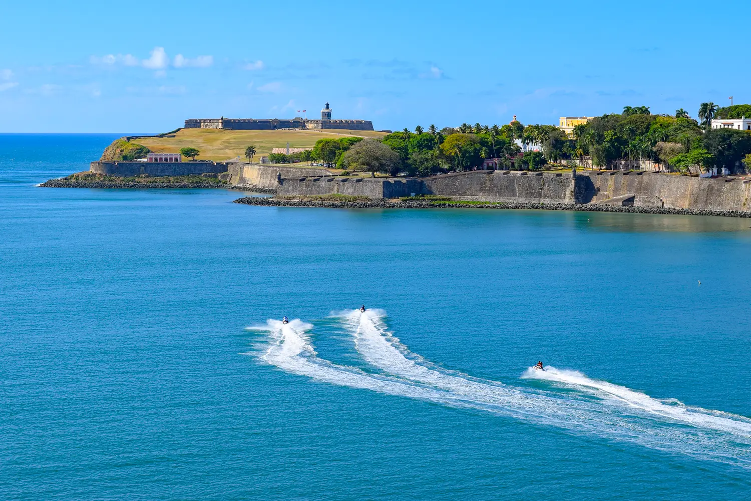 View of the promontory where the historic Castillo San Felipe del Morro is located in Old San Juan, as jet ski riders approach that direction.