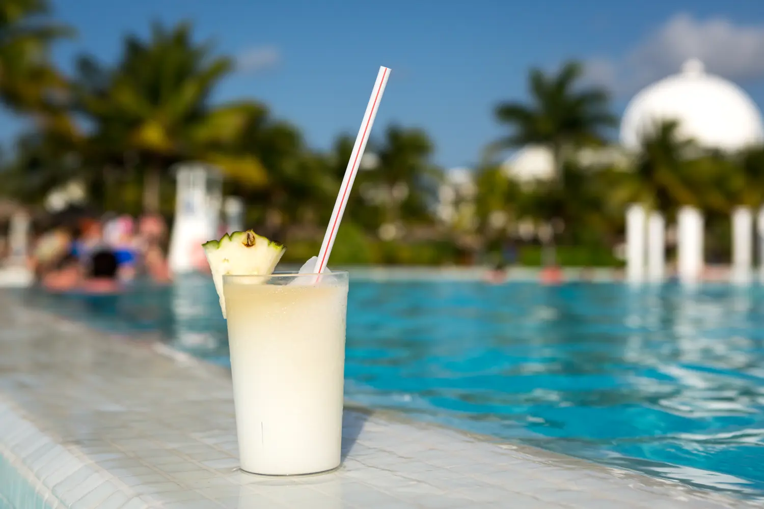 Glass of pinacolada cocktail standing by the swimming pool